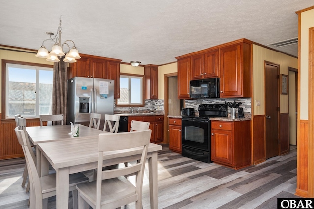 kitchen with a healthy amount of sunlight, black appliances, visible vents, and a wainscoted wall