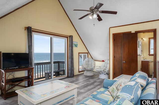 living area featuring wood walls, wood finished floors, a ceiling fan, vaulted ceiling, and ornamental molding