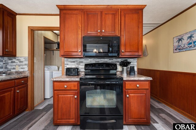 kitchen featuring wood finished floors, washing machine and clothes dryer, a textured ceiling, crown molding, and black appliances