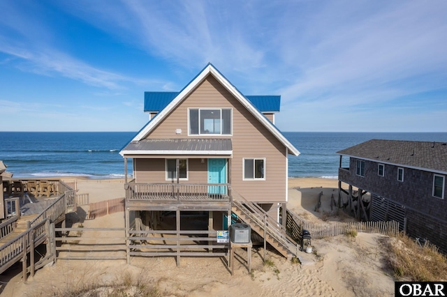 back of property with metal roof, a water view, cooling unit, and a view of the beach