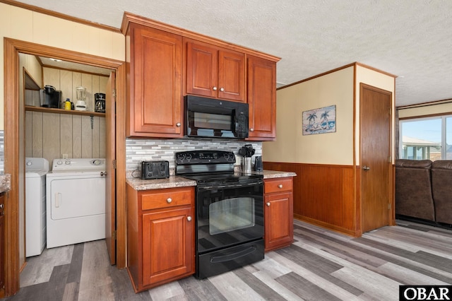 kitchen with crown molding, washer and clothes dryer, a textured ceiling, wood finished floors, and black appliances