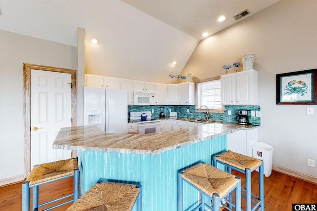 25224 Mac Oca Dr Lot 24, Waves, NC 27982 - kitchen featuring white appliances, a kitchen breakfast bar, backsplash, white cabinets, and lofted ceiling