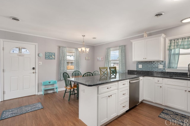 kitchen with a peninsula, visible vents, white cabinets, and a sink