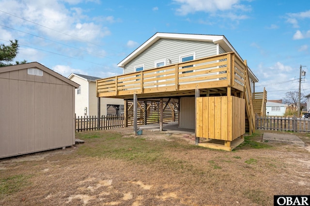 rear view of house featuring a deck, a shed, an outdoor structure, and fence