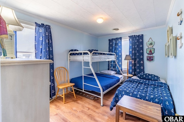 bedroom featuring crown molding, visible vents, and wood finished floors