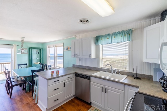 kitchen with decorative light fixtures, appliances with stainless steel finishes, white cabinetry, a sink, and a peninsula