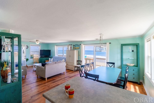 dining space with a textured ceiling, ceiling fan, wood finished floors, and baseboards