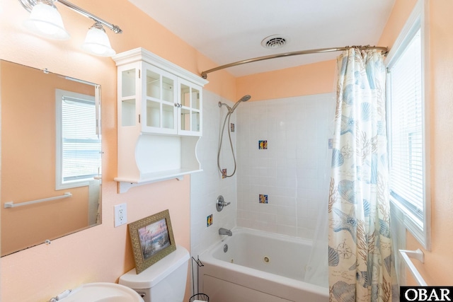 bathroom featuring toilet, shower / tub combo, a sink, and visible vents