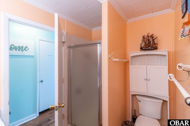 bathroom featuring a stall shower, crown molding, toilet, and wood finished floors