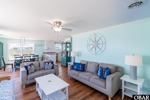 living room with ornamental molding, visible vents, dark wood finished floors, and a ceiling fan