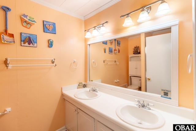 bathroom with ornamental molding, a sink, toilet, and double vanity