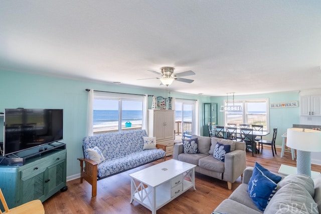 living room with ceiling fan, a water view, baseboards, and light wood-style floors