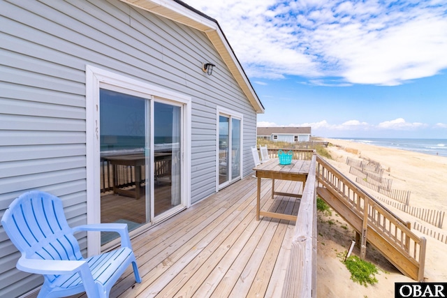 deck featuring a water view, stairway, and a beach view