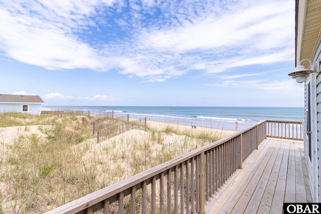 wooden deck featuring a beach view and a water view