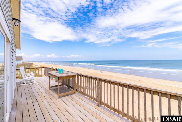 wooden deck with a water view and a beach view