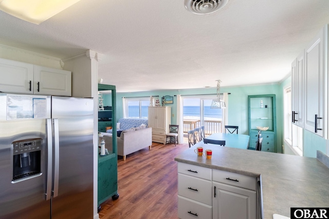 kitchen featuring visible vents, white cabinets, a water view, and stainless steel refrigerator with ice dispenser