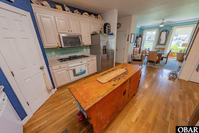 118 Neversail Way Lot 17, Coinjock, NC 27923 - kitchen featuring stainless steel appliances, light wood-style floors, decorative backsplash, ceiling fan, and ornamental molding
