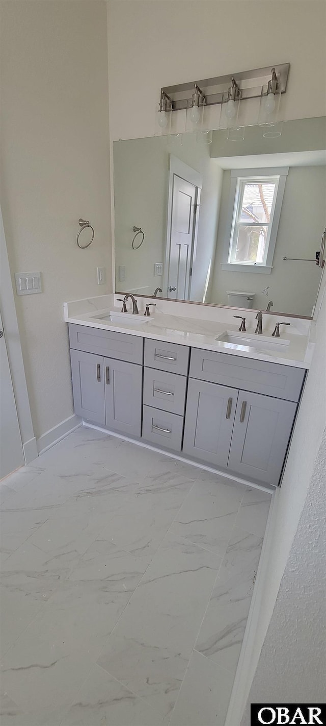 bathroom with double vanity, marble finish floor, and a sink