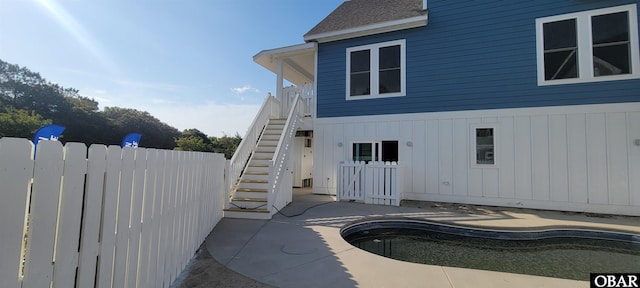 back of property with a patio, fence, an outdoor pool, and stairs