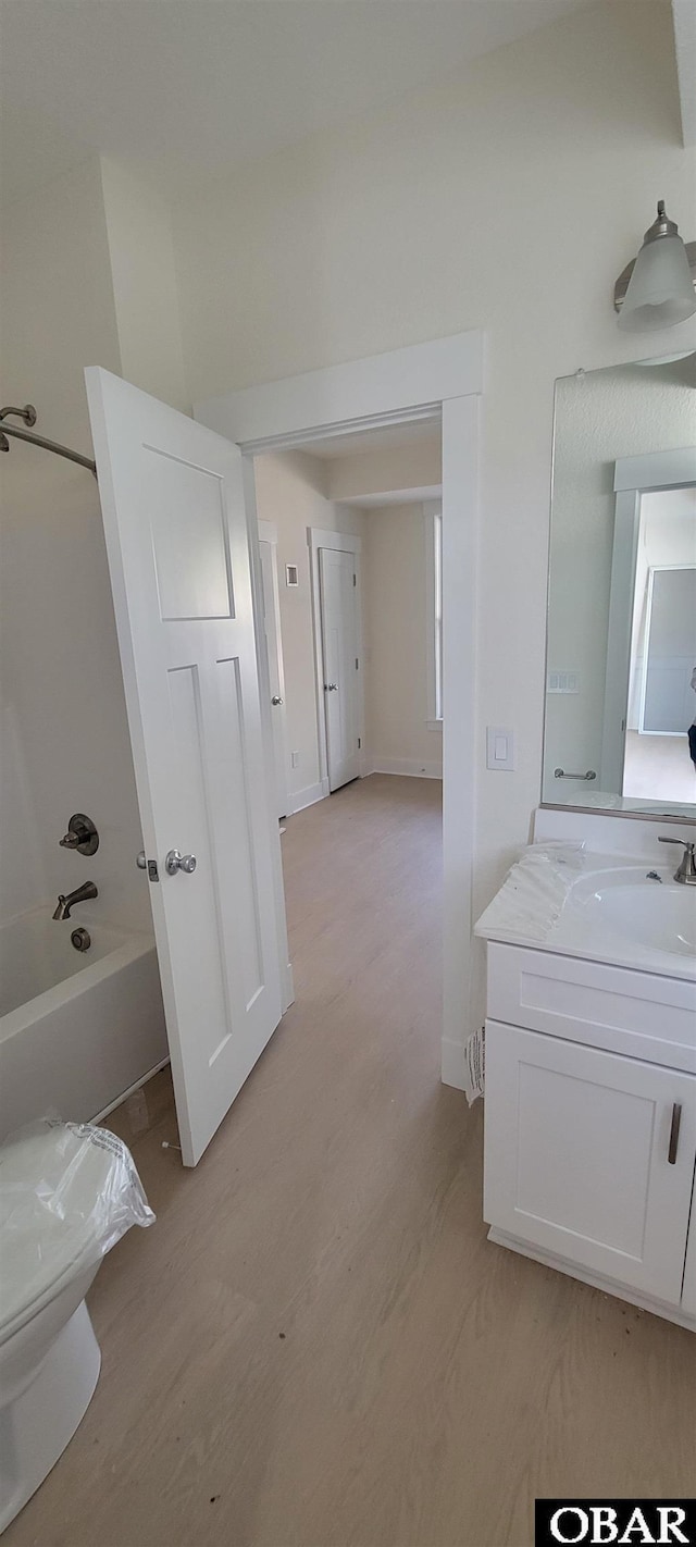 full bath with vanity, baseboards,  shower combination, and wood finished floors