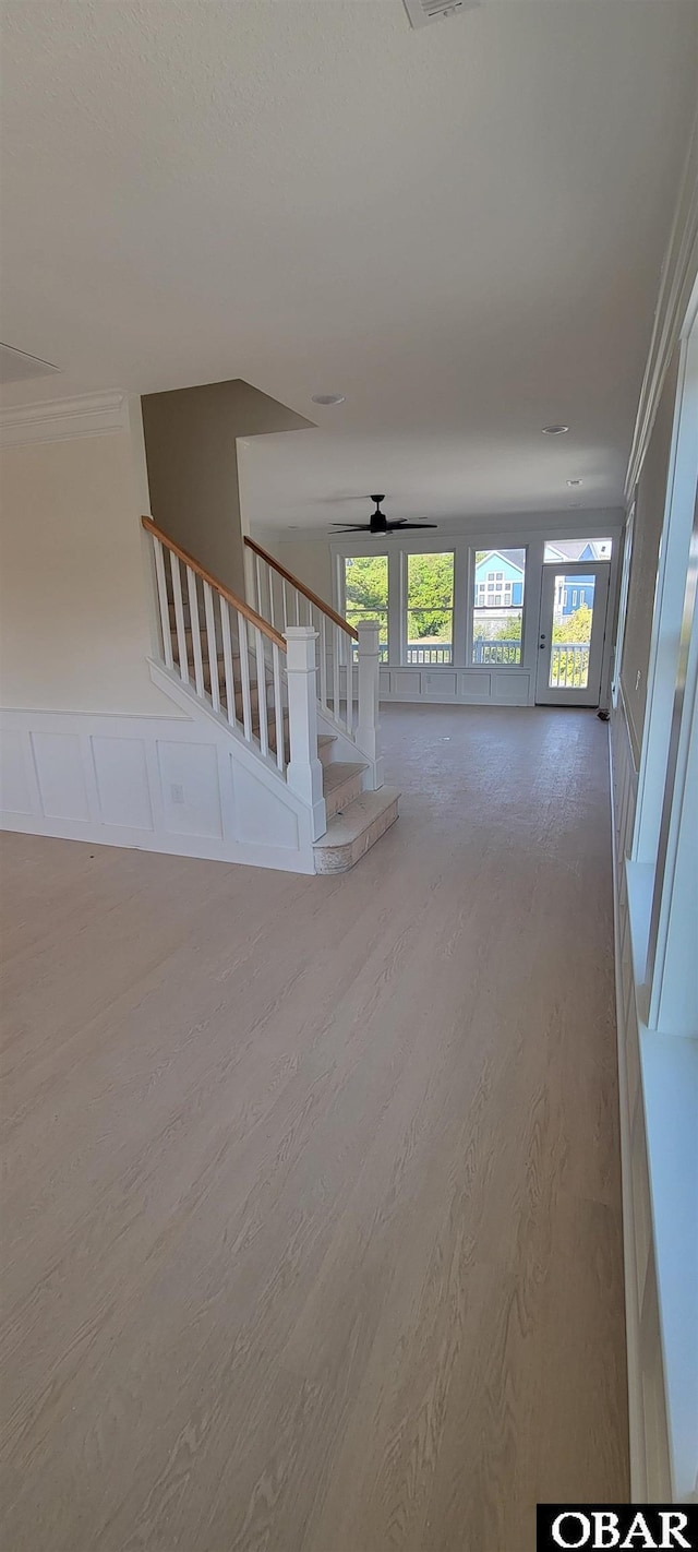 unfurnished living room with visible vents, wood finished floors, ceiling fan, and stairs