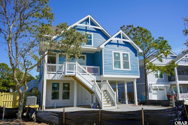 view of front of house featuring cooling unit, a carport, board and batten siding, fence private yard, and stairs