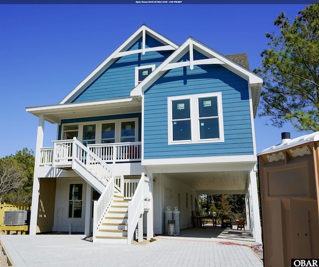 raised beach house with driveway, stairway, covered porch, and a carport
