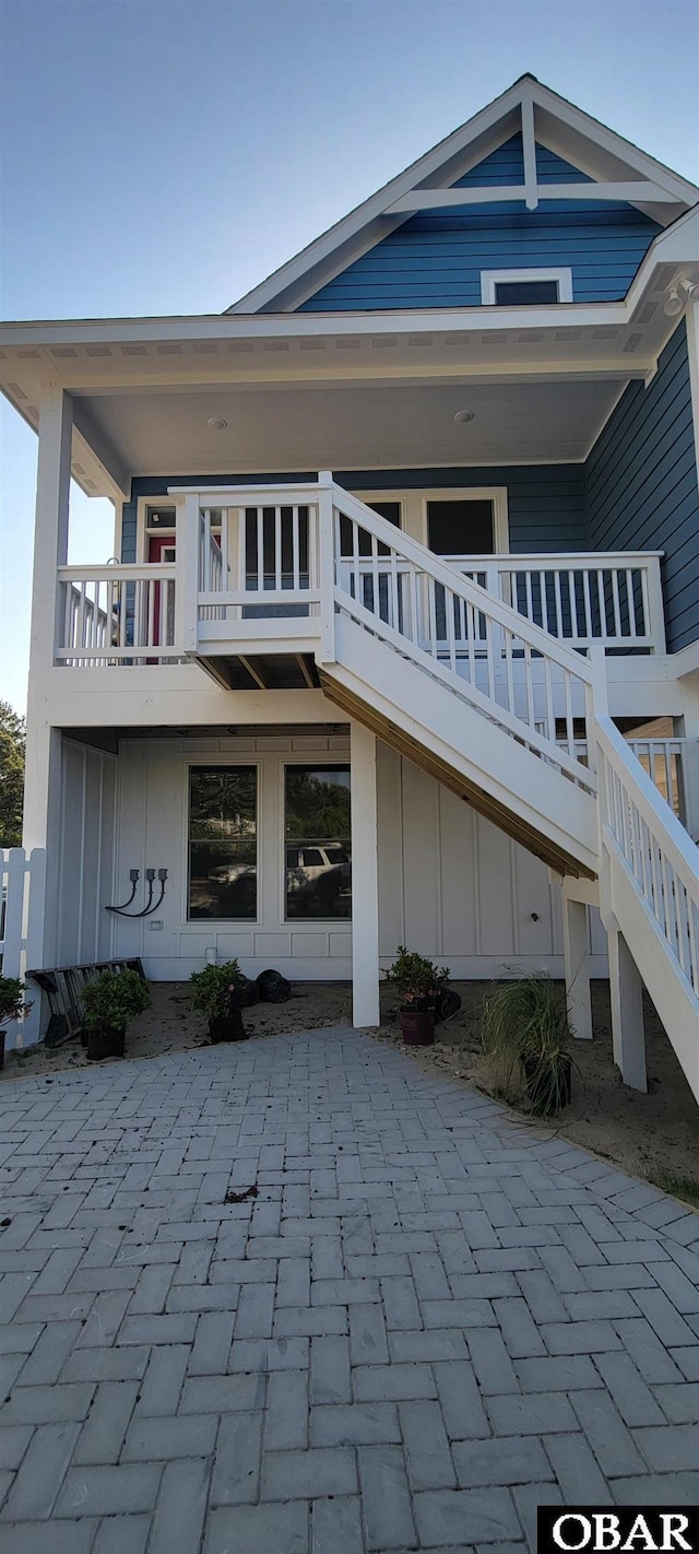 rear view of property with stairs and board and batten siding