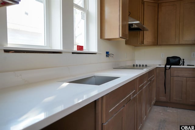 kitchen featuring wall chimney range hood, light countertops, and a healthy amount of sunlight