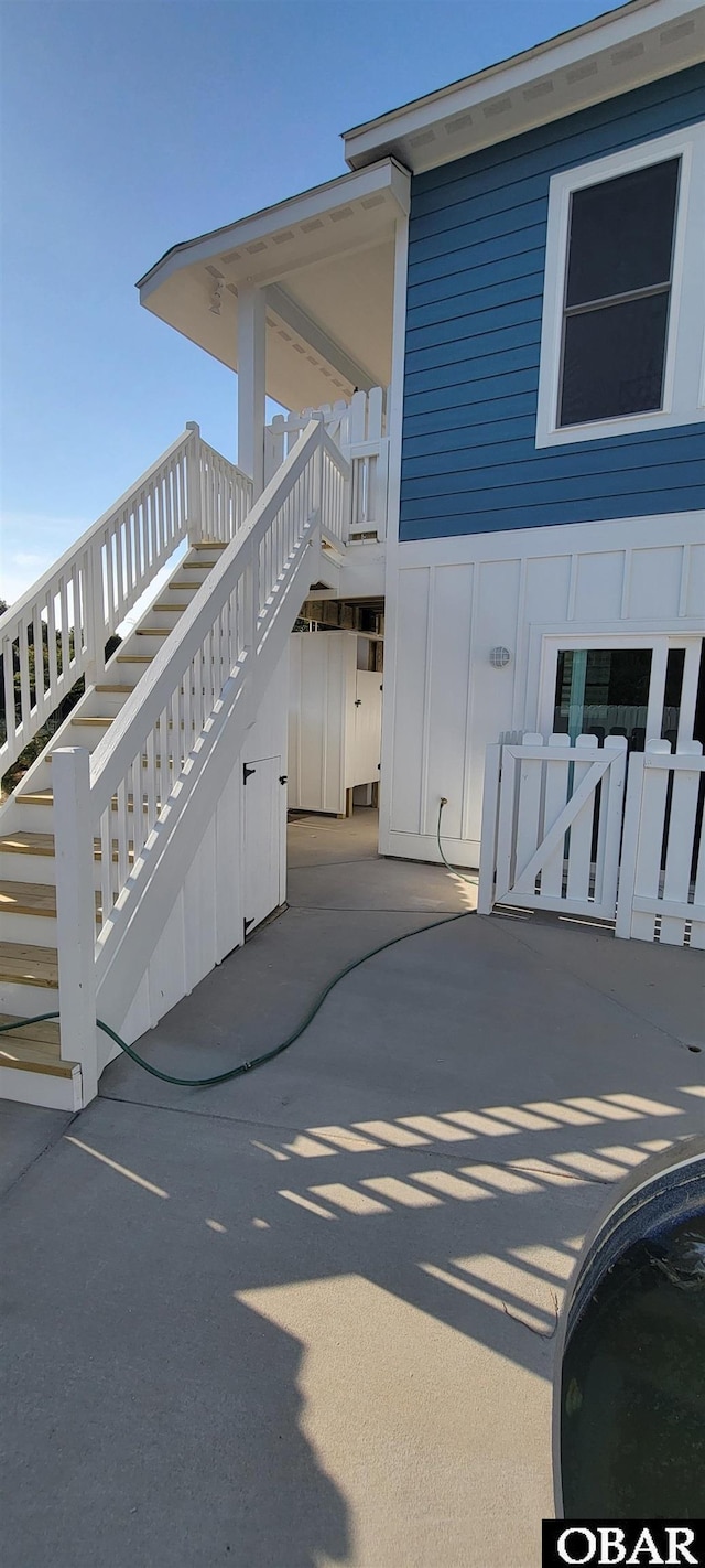 view of side of home with stairway, a patio, and board and batten siding