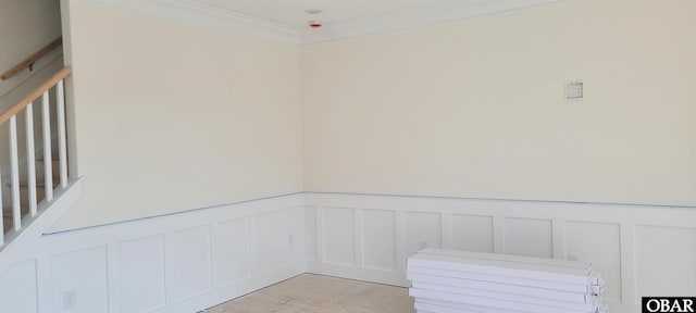 interior space featuring crown molding, a decorative wall, and a wainscoted wall