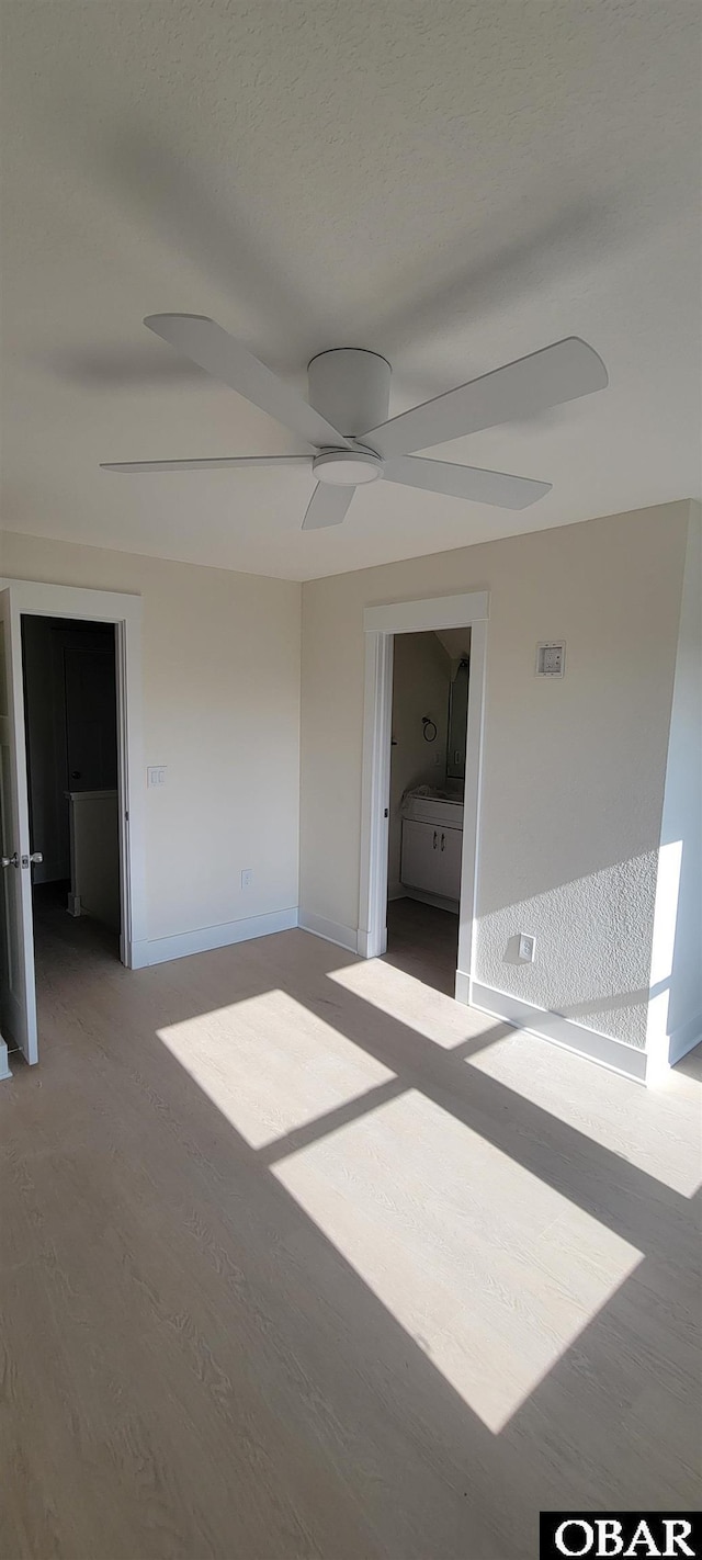unfurnished bedroom with connected bathroom, wood finished floors, and ceiling fan