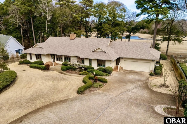 view of front of house with a garage, concrete driveway, roof with shingles, and fence