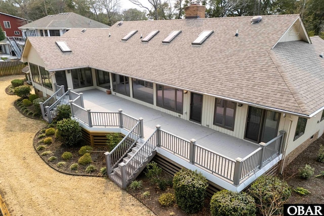 back of house with a chimney, a shingled roof, stairway, a sunroom, and a wooden deck