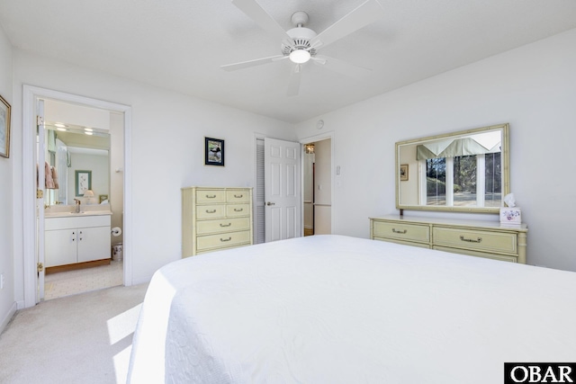 bedroom featuring a sink, ensuite bath, a ceiling fan, and light colored carpet