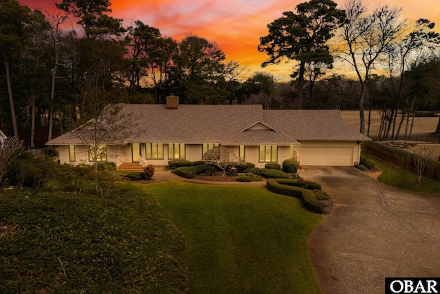 ranch-style home with a garage, a front yard, driveway, and a chimney