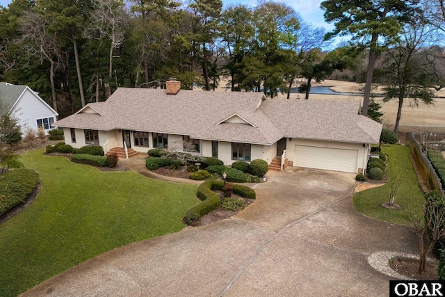 view of front of home featuring a garage, fence, driveway, a chimney, and a front yard