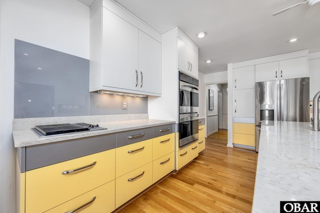 kitchen featuring stainless steel appliances, light stone counters, and light wood-style flooring