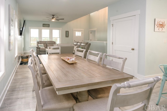 dining area featuring a ceiling fan, light wood-style flooring, and baseboards