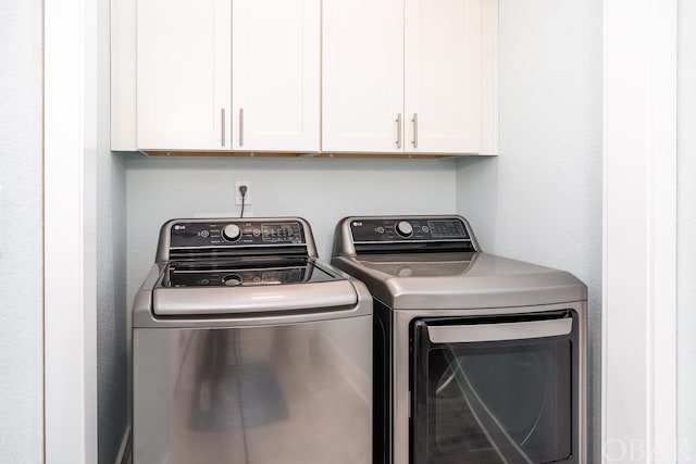 washroom with washer and clothes dryer and cabinet space