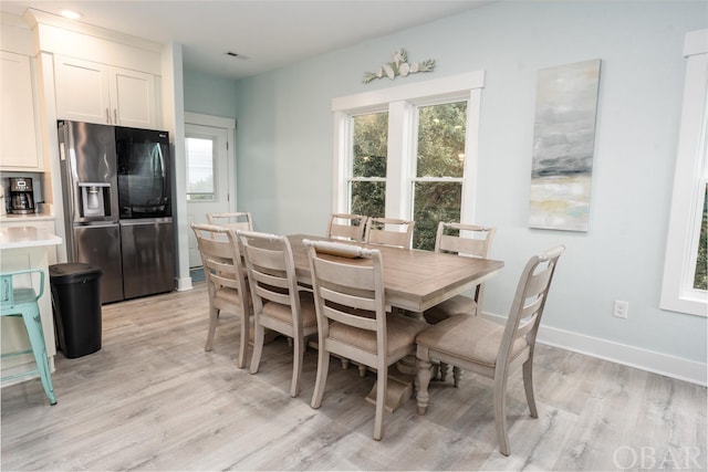 dining space with visible vents, light wood-style flooring, and baseboards