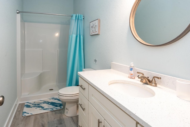 bathroom with toilet, a stall shower, wood finished floors, and vanity