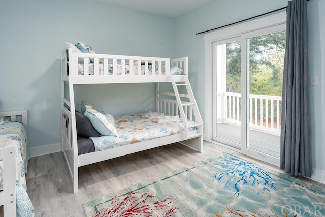 bedroom with access to exterior, baseboards, and wood finished floors