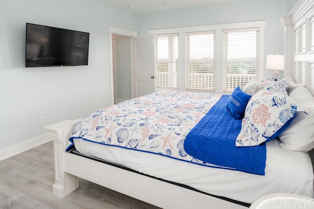 bedroom featuring light wood-style flooring, multiple windows, and baseboards