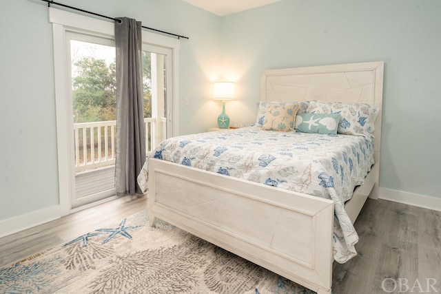 bedroom featuring baseboards, wood finished floors, and access to exterior