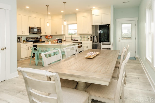 dining space featuring baseboards, light wood-style flooring, and recessed lighting