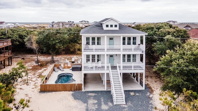 rear view of property with a shingled roof, a patio, a balcony, stairway, and fence private yard