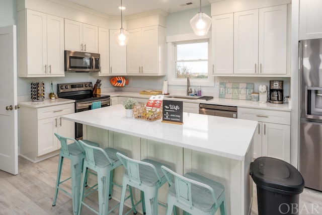 kitchen with white cabinets, appliances with stainless steel finishes, pendant lighting, and a center island