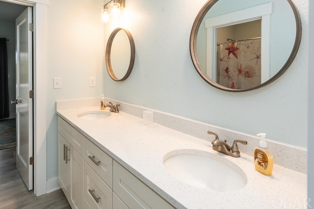 bathroom with double vanity, curtained shower, a sink, and wood finished floors