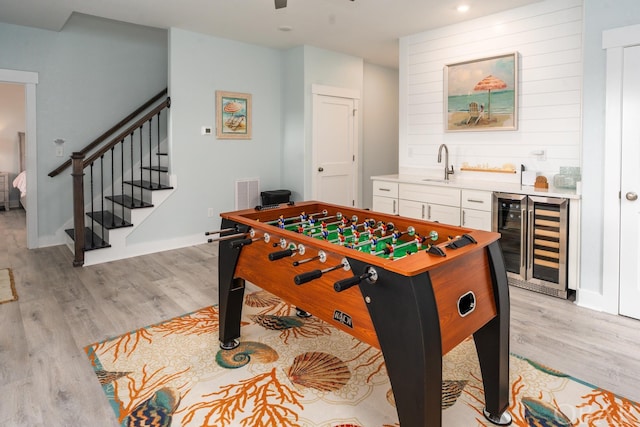 playroom featuring beverage cooler, indoor wet bar, a sink, and light wood-style floors